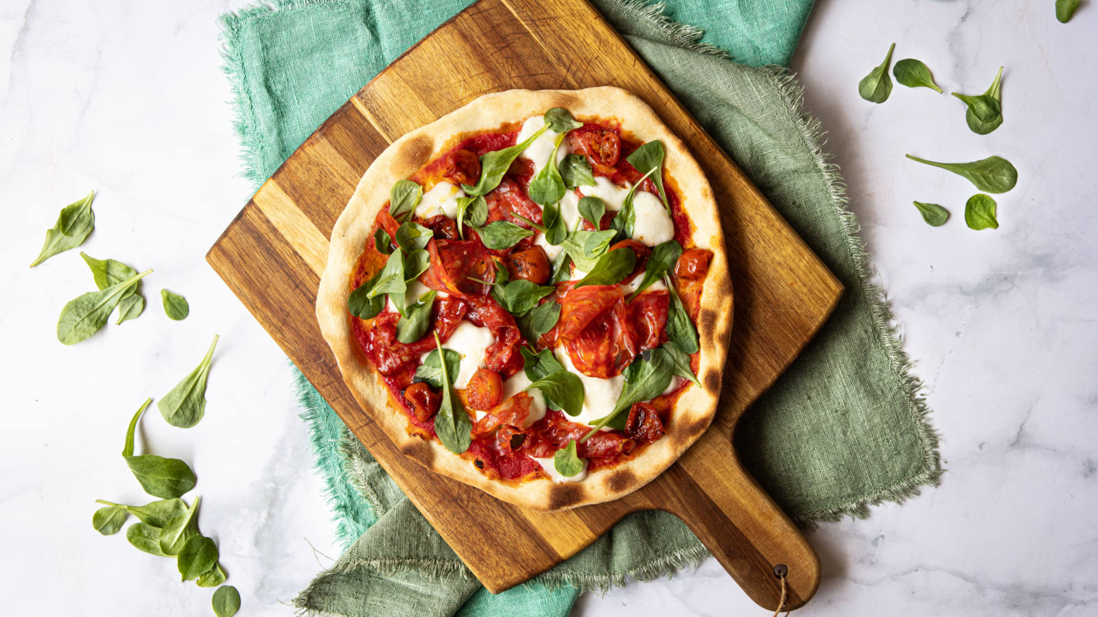 Pizza fatta in casa con spianata calabrese, mozzarella e pomodori confit